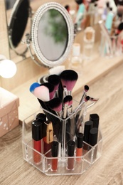 Photo of Organizer with cosmetic products for makeup on table near mirror