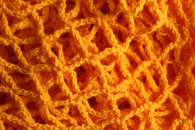 Photo of Orange knitted net as background, closeup view