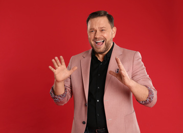 Portrait of screaming mature man on red background