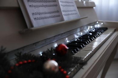 Photo of White grand piano with festive decor indoors, closeup. Christmas music