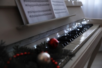 White grand piano with festive decor indoors, closeup. Christmas music