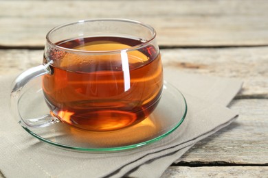 Aromatic tea in glass cup and napkin on wooden table