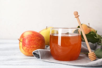 Photo of Glass of honey, apples and dipper on wooden table