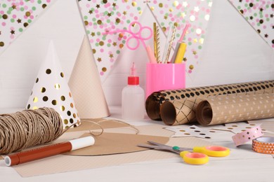Photo of Stationery and different materials to create party hats on white wooden table. Handmade decoration