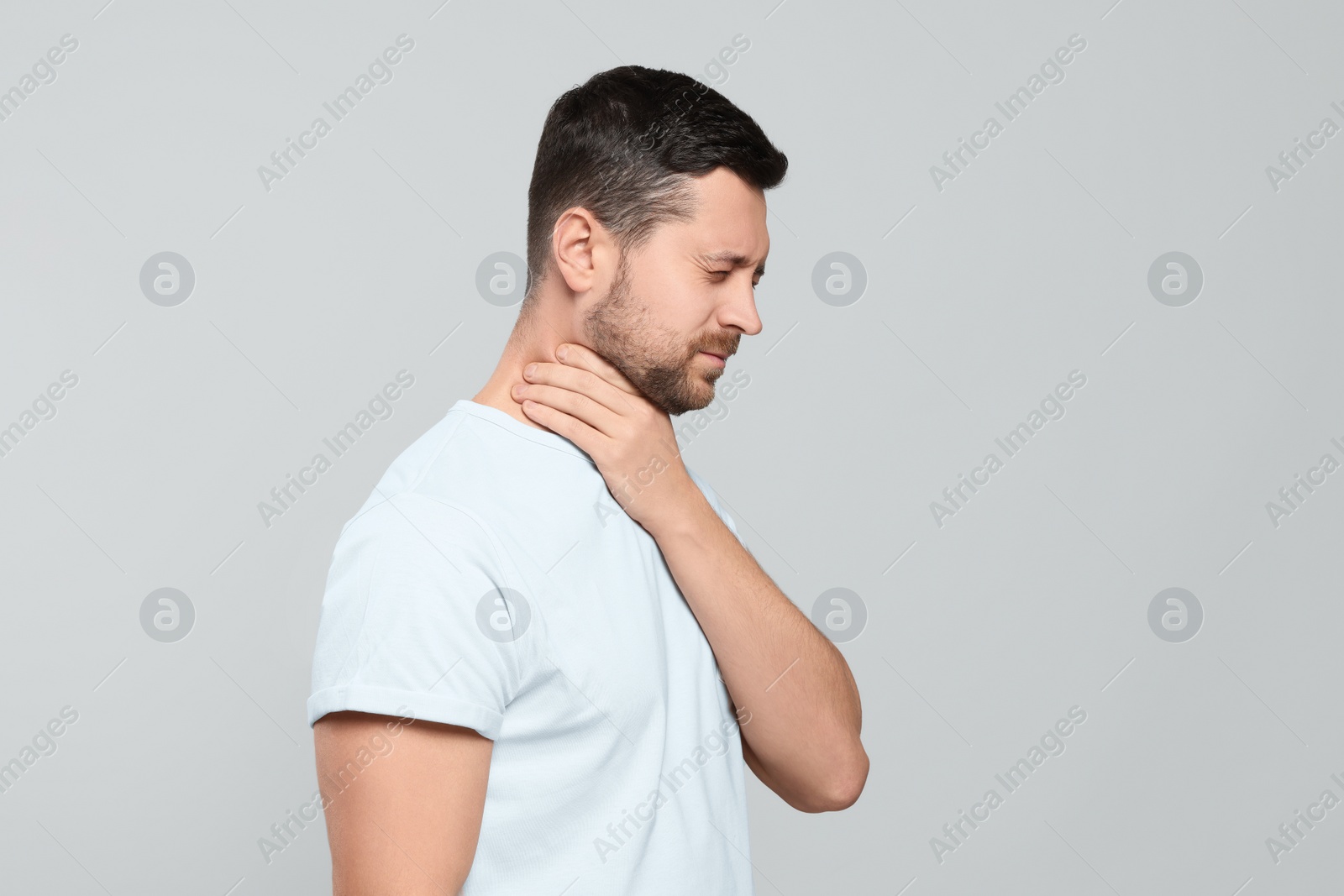 Photo of Man suffering from sore throat on light gray background