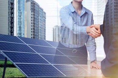 Image of Double exposure of businesspeople shaking hands and solar panels installed outdoors. Alternative energy source