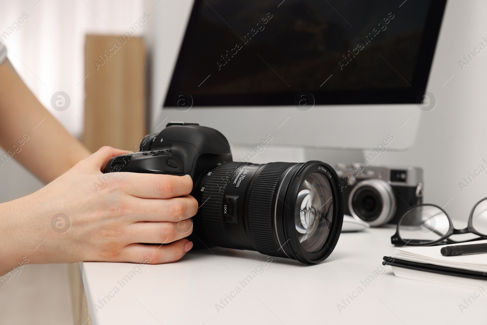 Photo of Photographer with camera at white table indoors, closeup