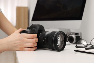 Photographer with camera at white table indoors, closeup