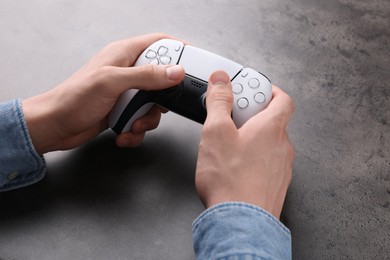 Man using wireless game controller at grey table, closeup