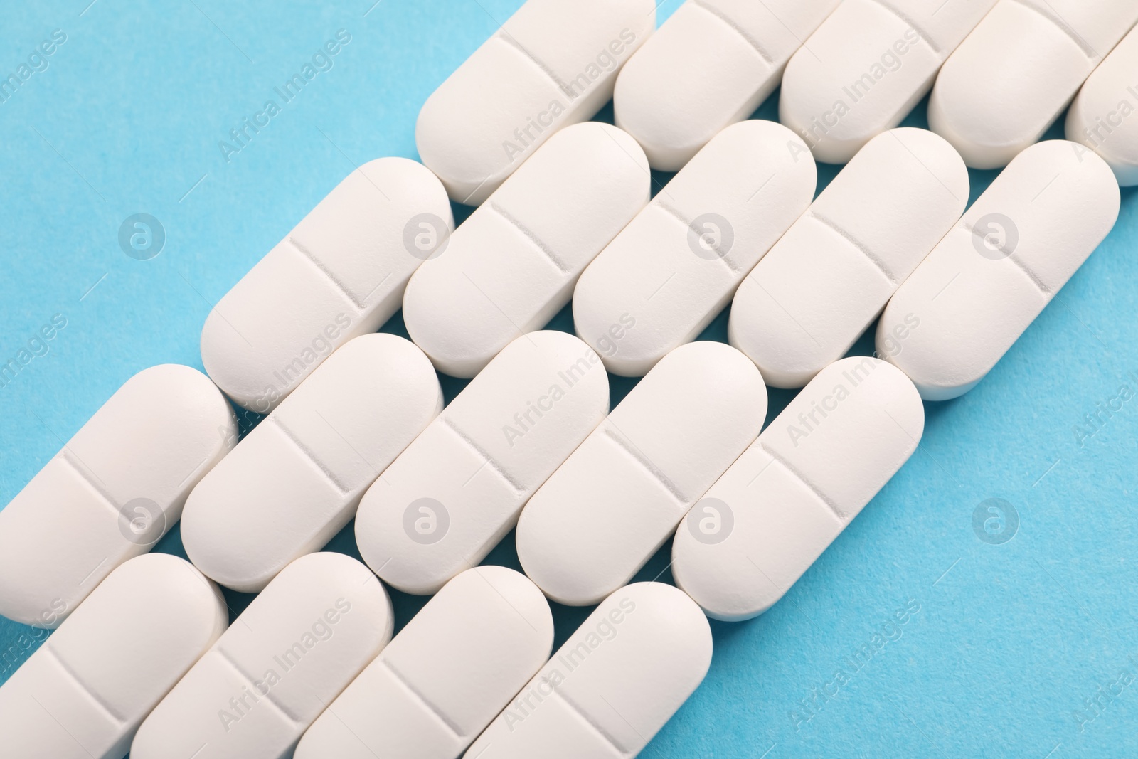 Photo of White pills on light blue background, flat lay