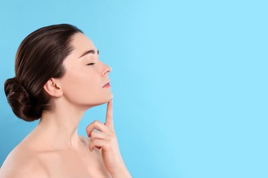 Photo of Young woman massaging her face on turquoise background. Space for text