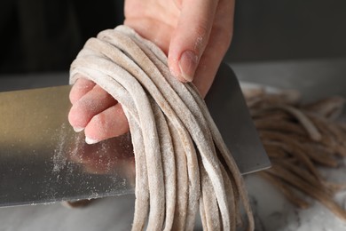 Photo of Woman making soba (buckwheat noodles) at table, closeup