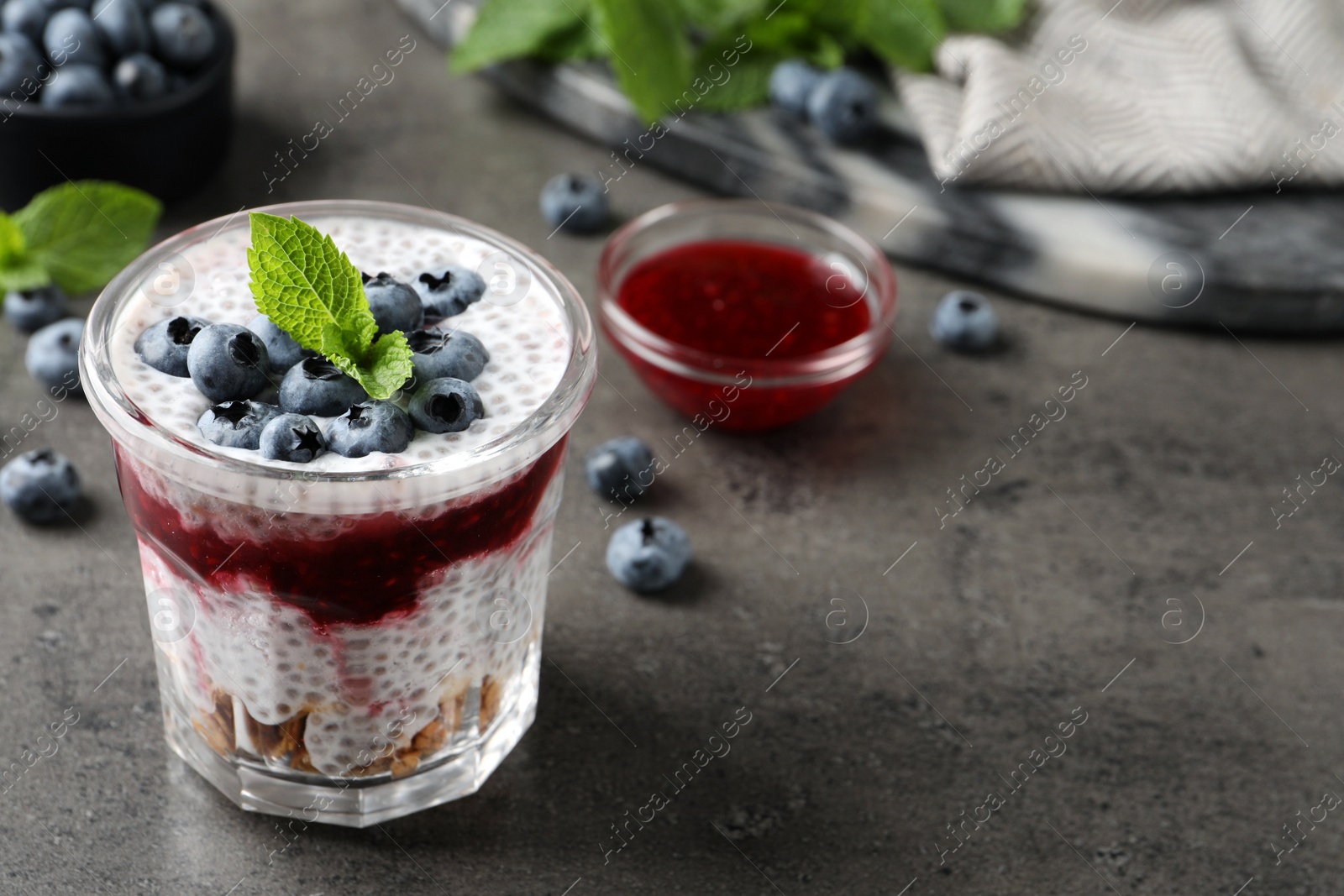Photo of Delicious chia pudding with blueberries on grey table. Space for text
