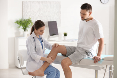 Female orthopedist examining patient's leg in clinic