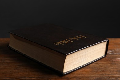 Photo of Hardcover Bible on wooden table against black background