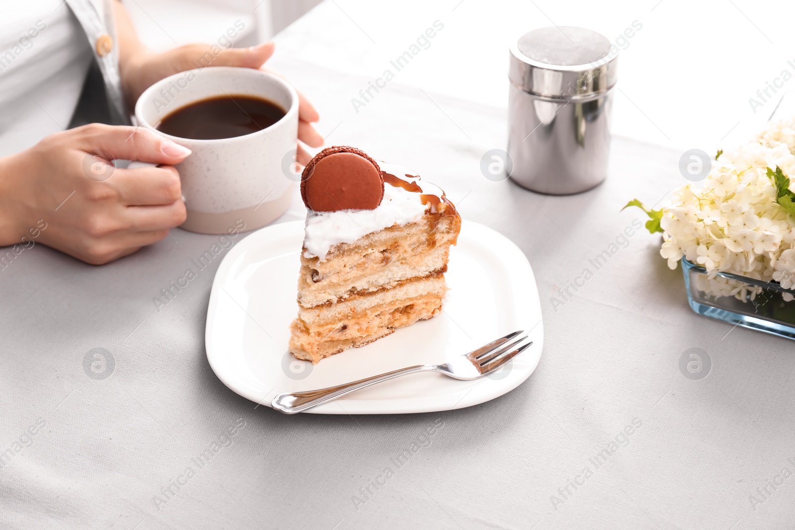 Photo of Woman eating delicious homemade cake with caramel sauce at table