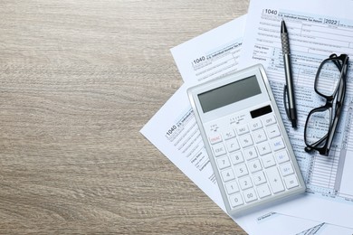 Photo of Calculator, documents, glasses and pen on wooden table, flat lay with space for text. Tax accounting