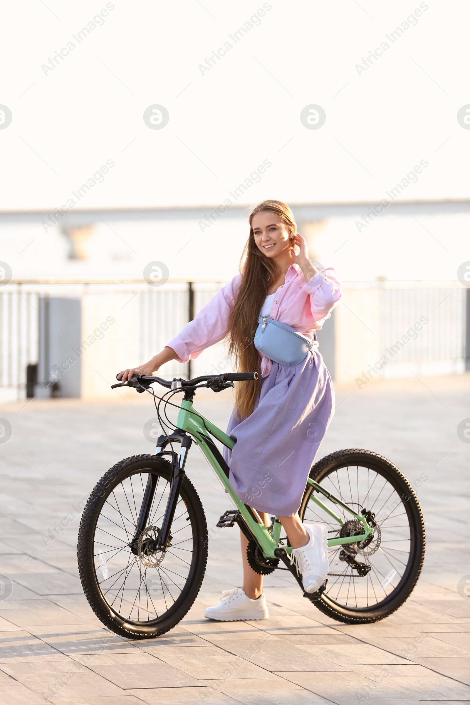 Photo of Young woman riding bicycle in city on sunny day