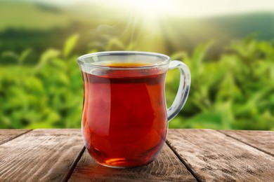 Image of Cup of hot freshly brewed rooibos tea on wooden table outdoors