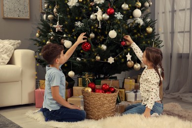 Photo of Cute little children decorating Christmas tree at home