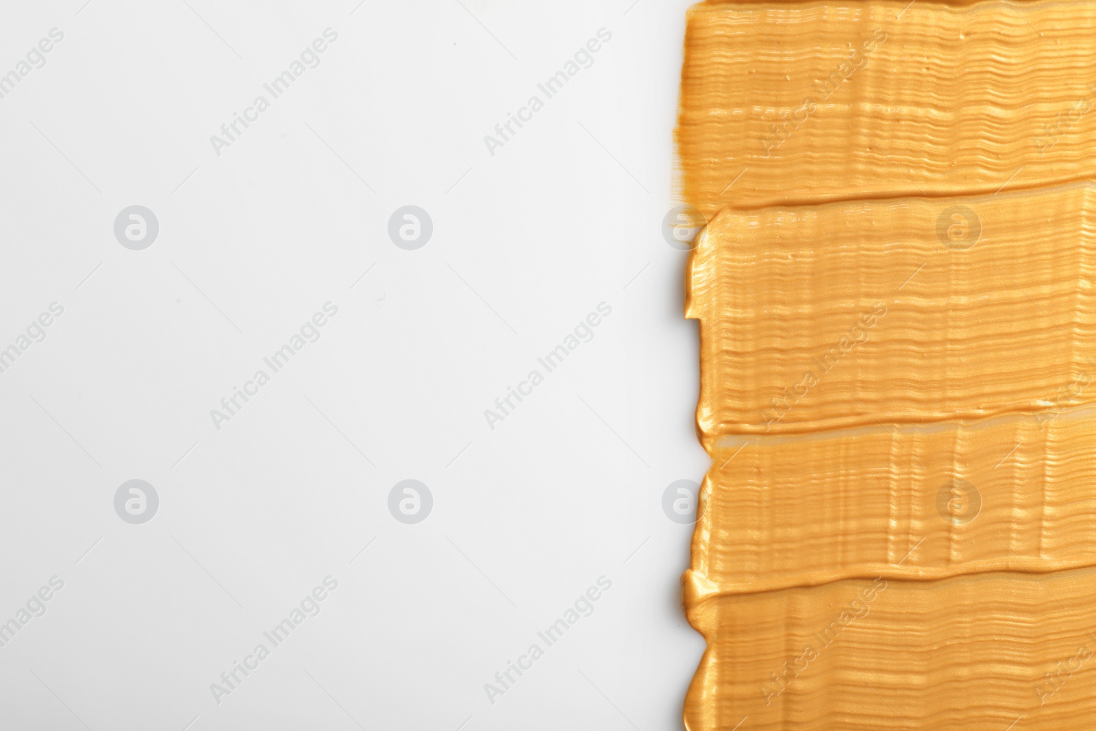 Photo of Strokes of gold paint isolated on white, top view