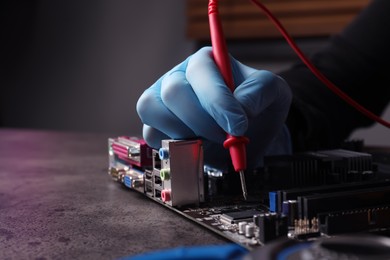 Photo of Technician repairing electronic circuit board at table, closeup