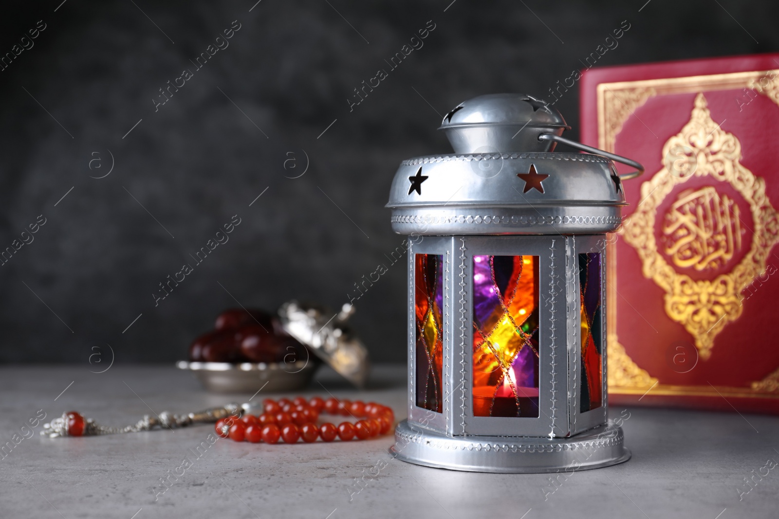 Photo of Arabic lantern, quran and misbaha on grey table. Space for text