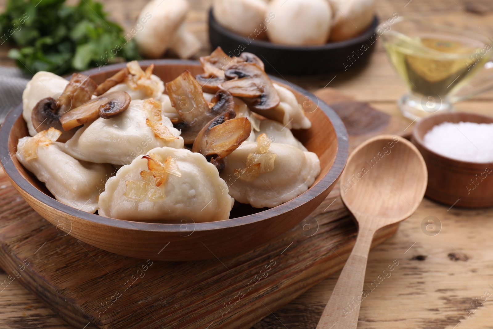 Photo of Delicious dumplings (varenyky) with potatoes, onion and mushrooms served on wooden table