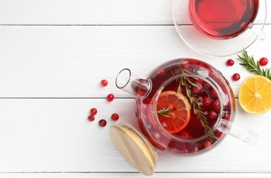 Photo of Tasty hot cranberry tea with lemon, rosemary and fresh berries on white wooden table