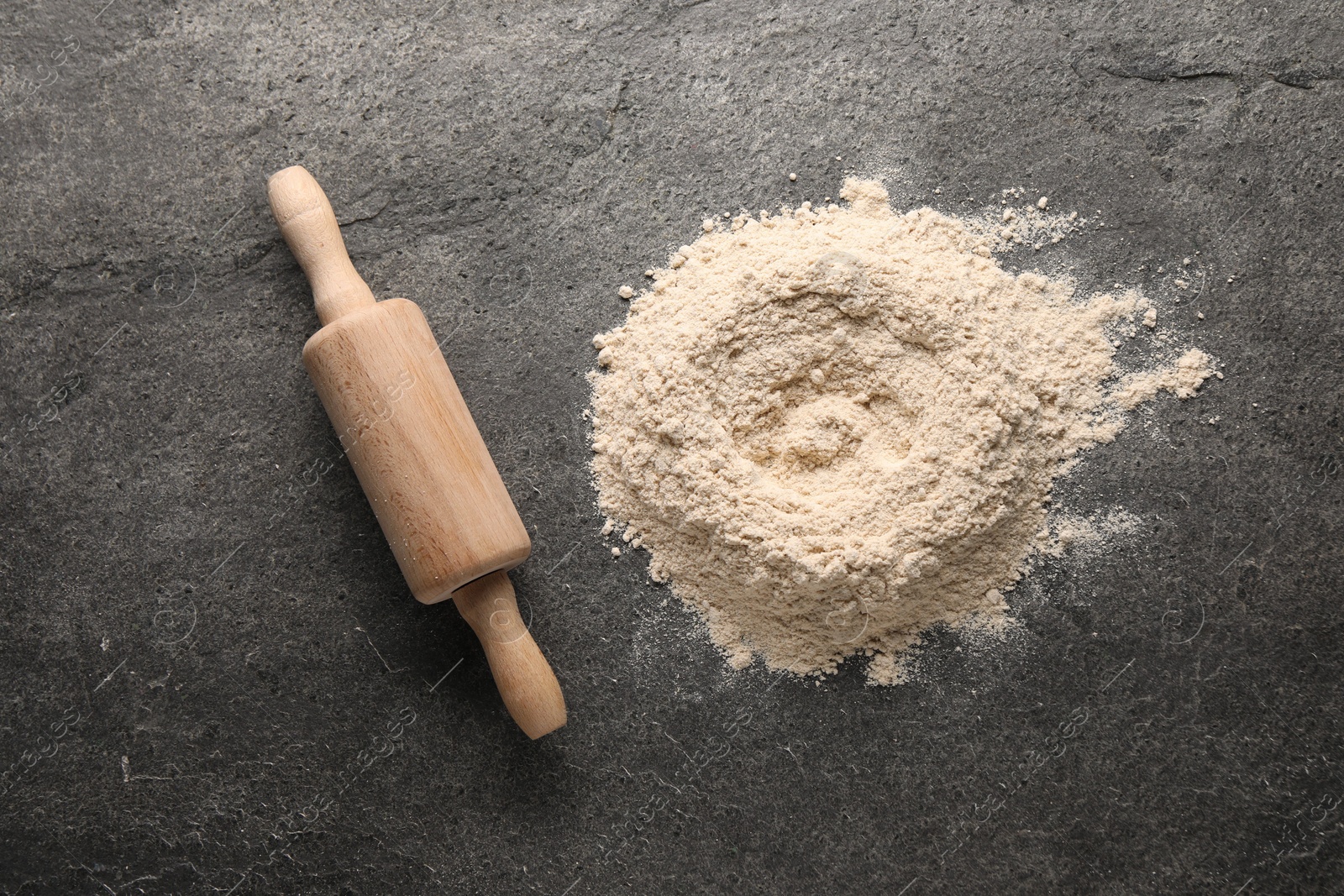 Photo of Pile of flour and rolling pin on grey textured table, top view