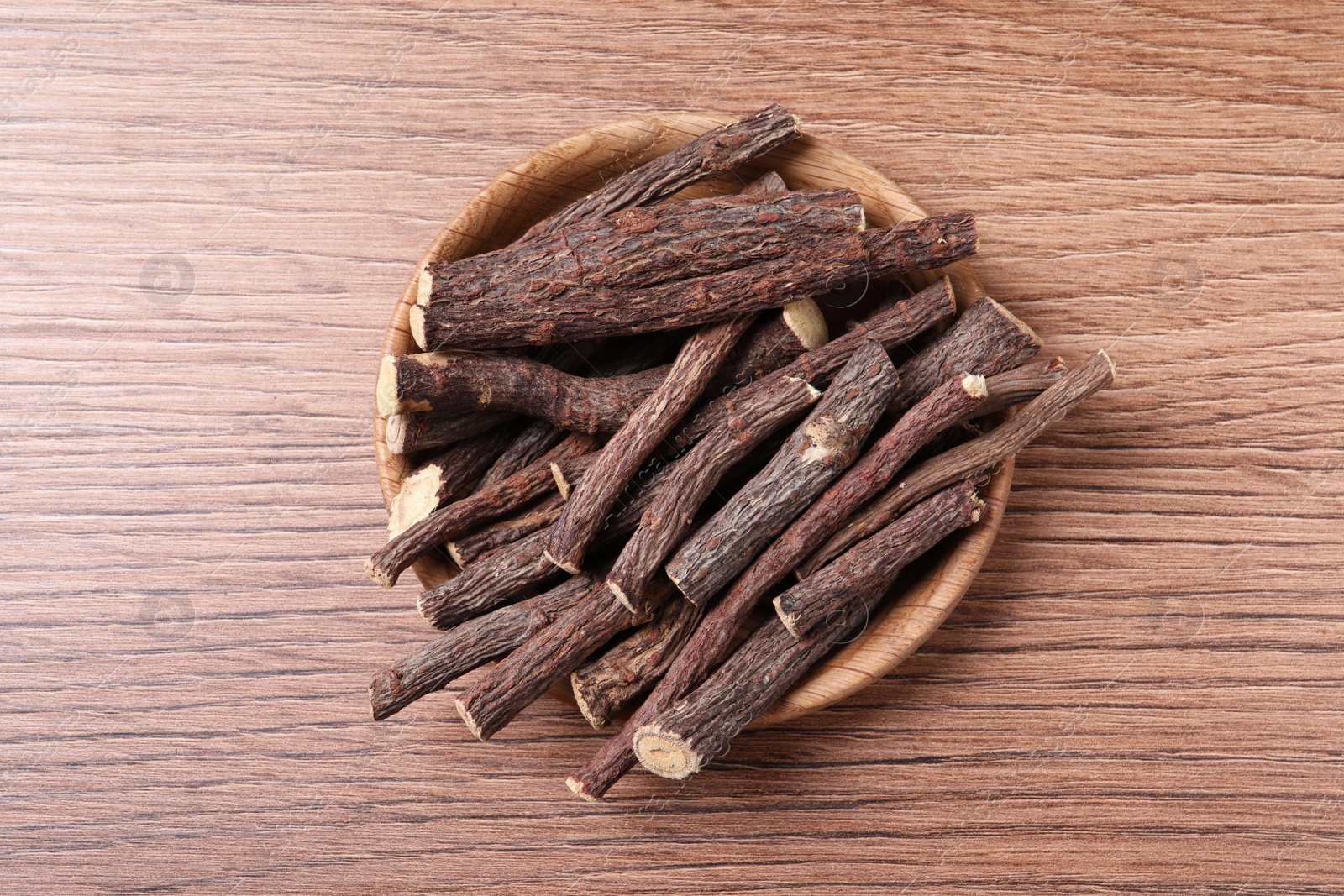 Photo of Dried sticks of liquorice root on wooden table, top view