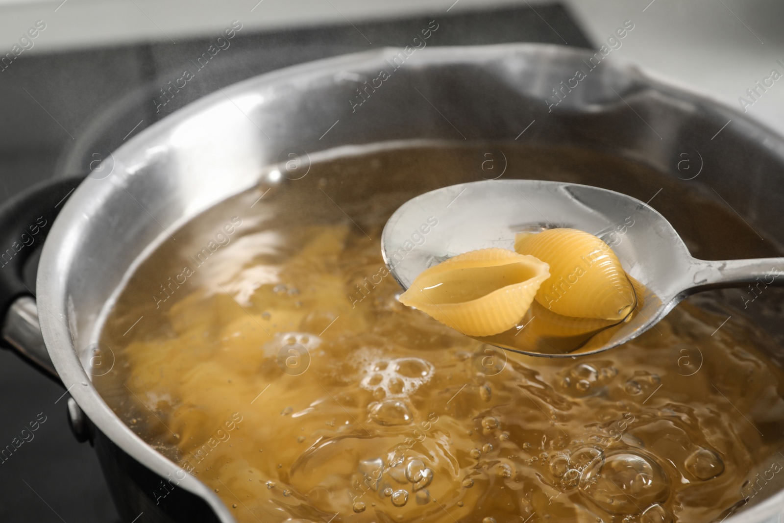 Photo of Cooking pasta in pot on stove, closeup view