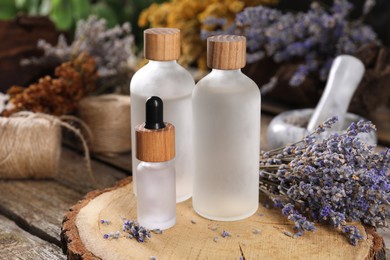 Photo of Bottles of essential oils and dry lavender flowers on wooden table. Medicinal herbs