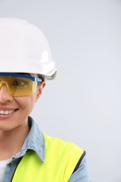 Female industrial engineer in uniform on light background, space for text. Safety equipment