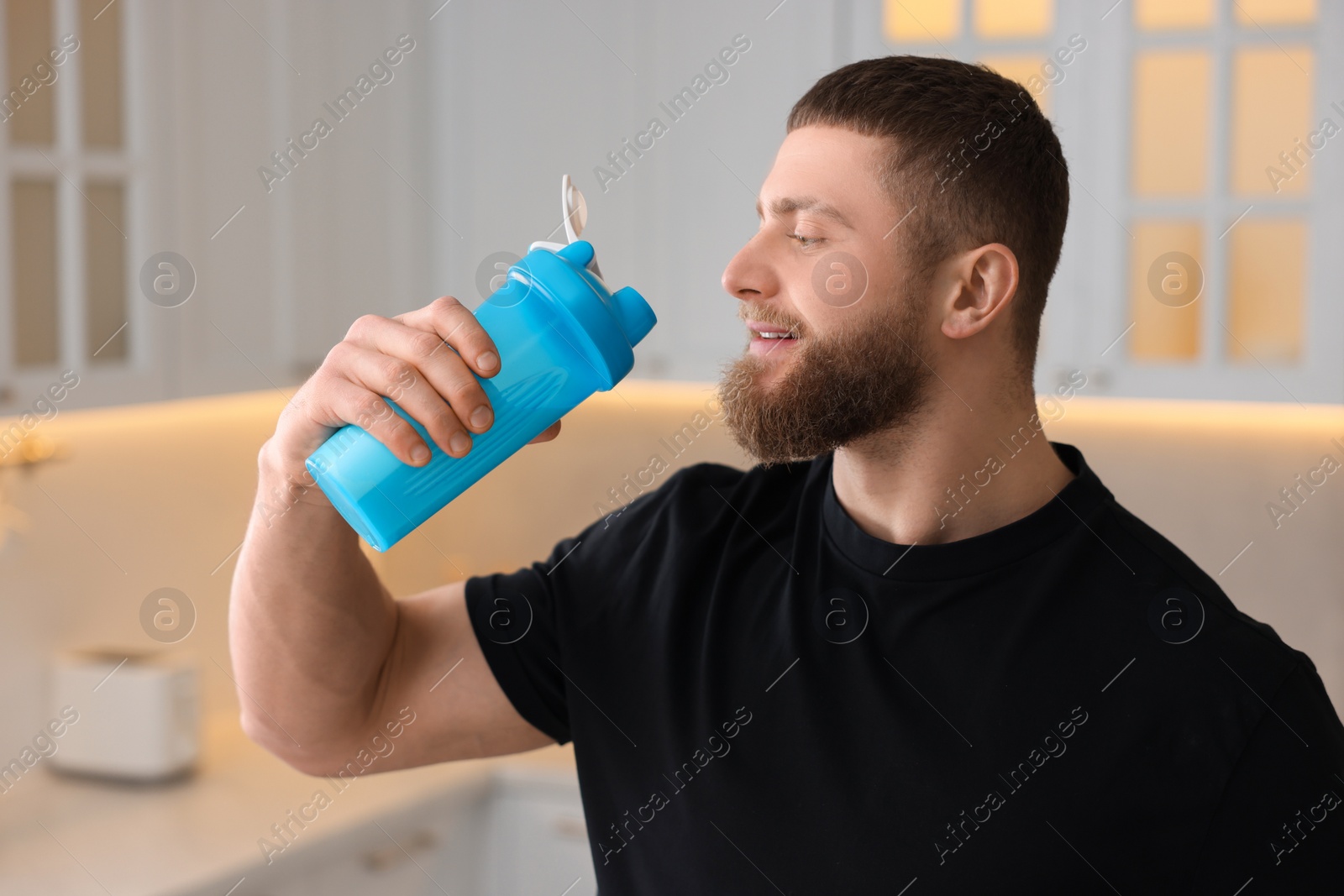 Photo of Young man with shaker of protein in kitchen