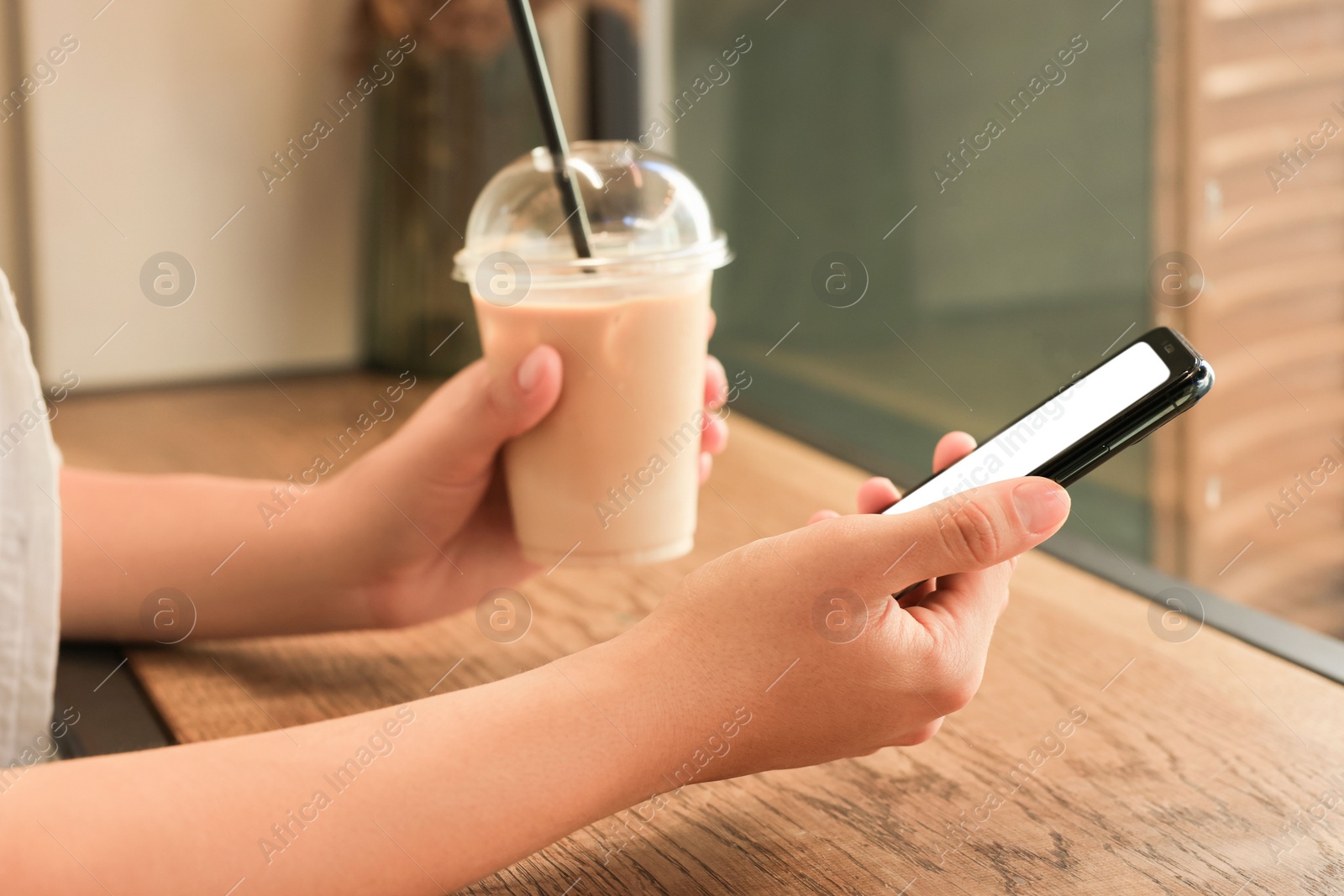 Photo of Woman using smartphone near window in cafe, closeup