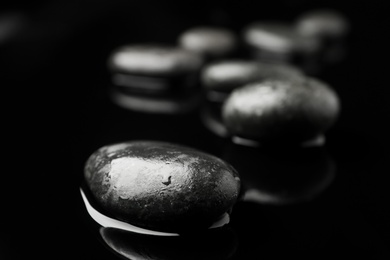 Photo of Wet spa stones on black background. Space for text