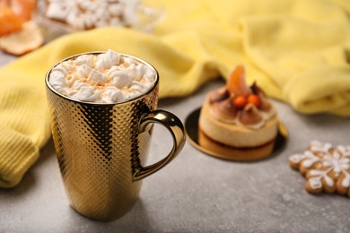 Photo of Delicious marshmallow drink and yellow sweater on light grey table