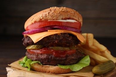 Photo of Tasty cheeseburger with patties, French fries and pickle on tree stump, closeup
