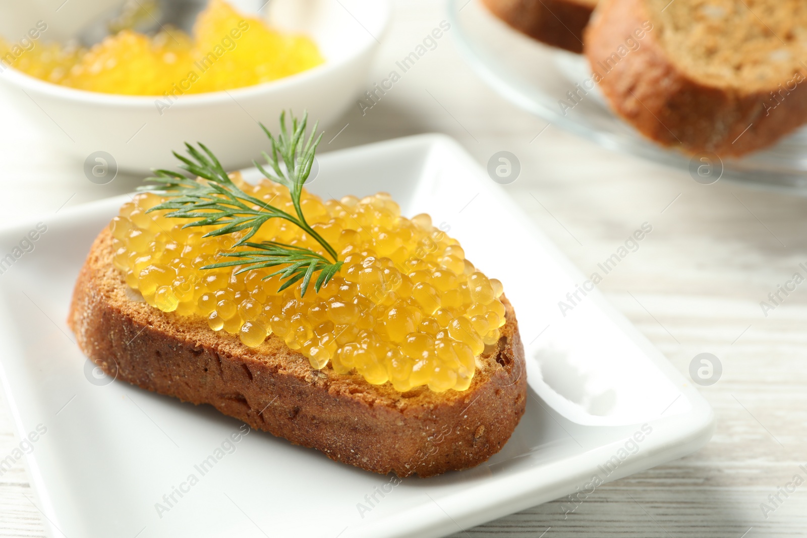 Photo of Slice of bread with pike caviar on white wooden table, closeup