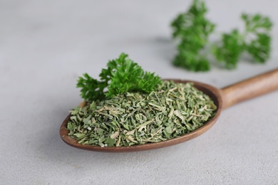 Photo of Spoon with dry parsley on grey table