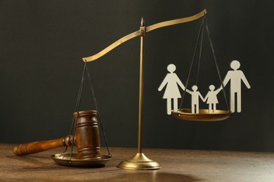 Divorce concept. Scales, paper cutout of family and gavel on wooden table