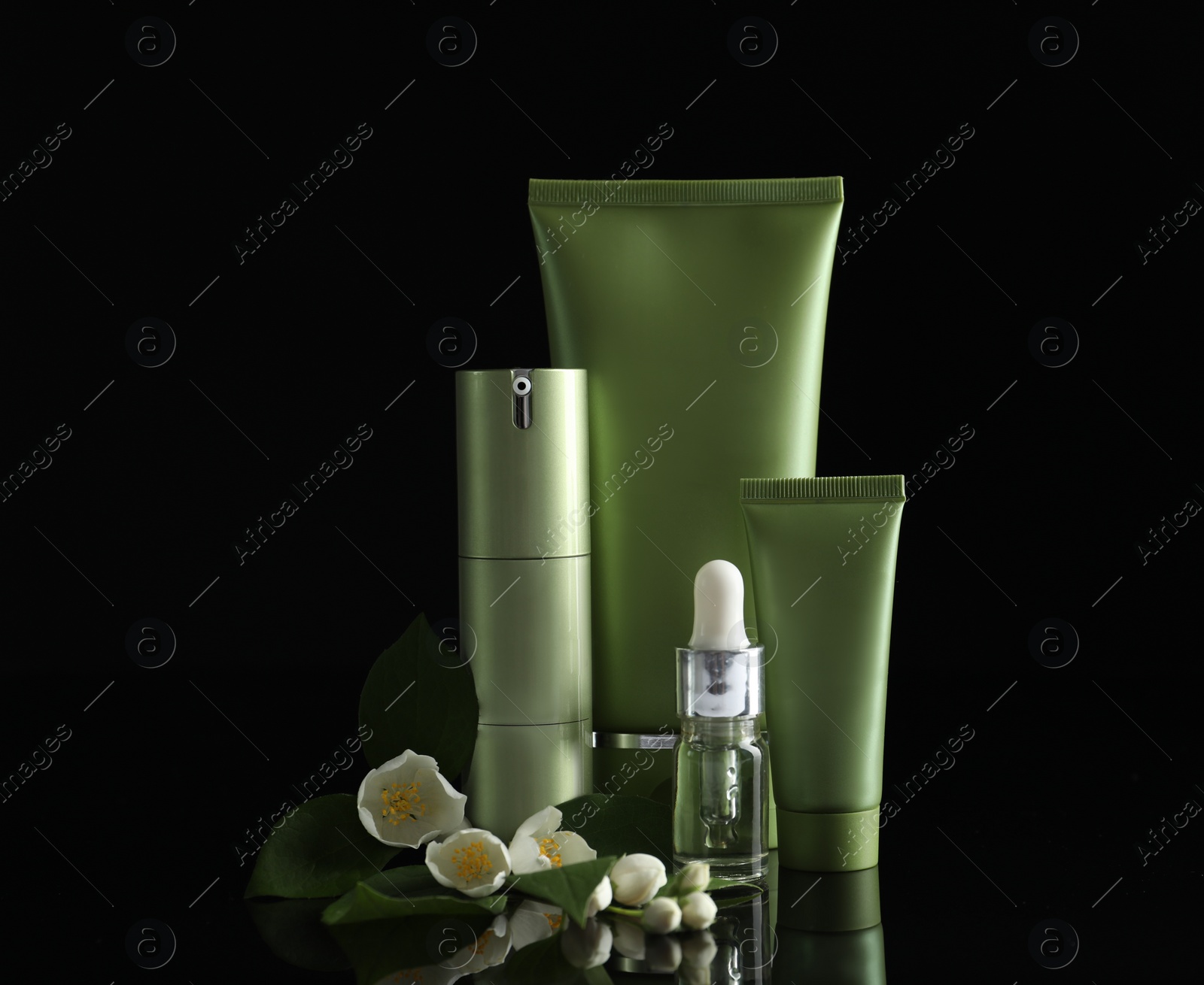 Photo of Set of cosmetic products and flowers on black background