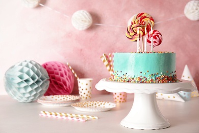 Stand with fresh delicious cake and birthday decorations on table. Space for text