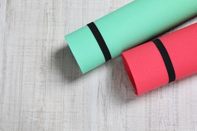 Photo of Bright rolled camping mats on white wooden background, flat lay