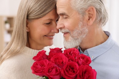 Affectionate senior couple with beautiful bouquet at home