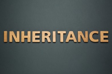 Photo of Word Inheritance made with wooden letters on black background, flat lay