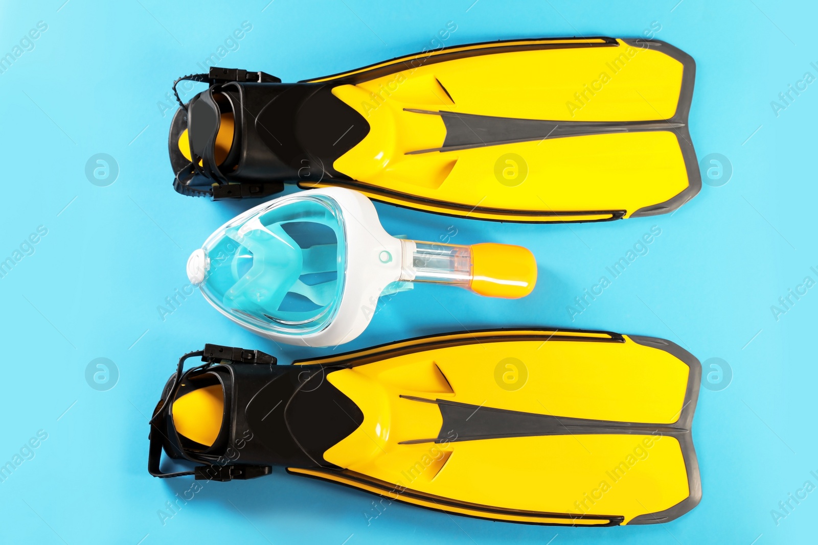 Photo of Pair of yellow flippers and diving mask on color background, top view