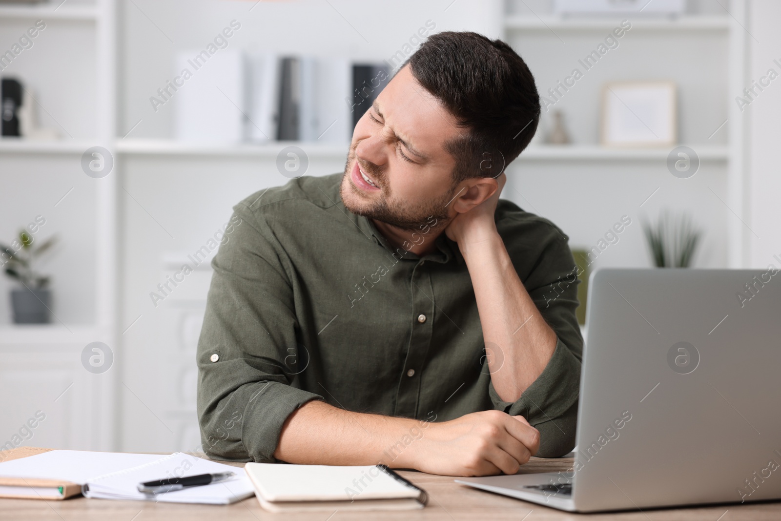 Photo of Man suffering from neck pain in office