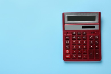 Red calculator on light blue background, top view. Space for text